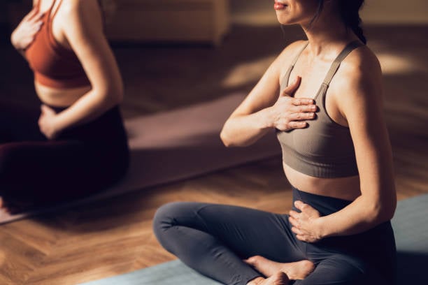 person sitting cross-legged on a yoga mat practicing mindful breathing during a Nord Pilates session indoors.jpg